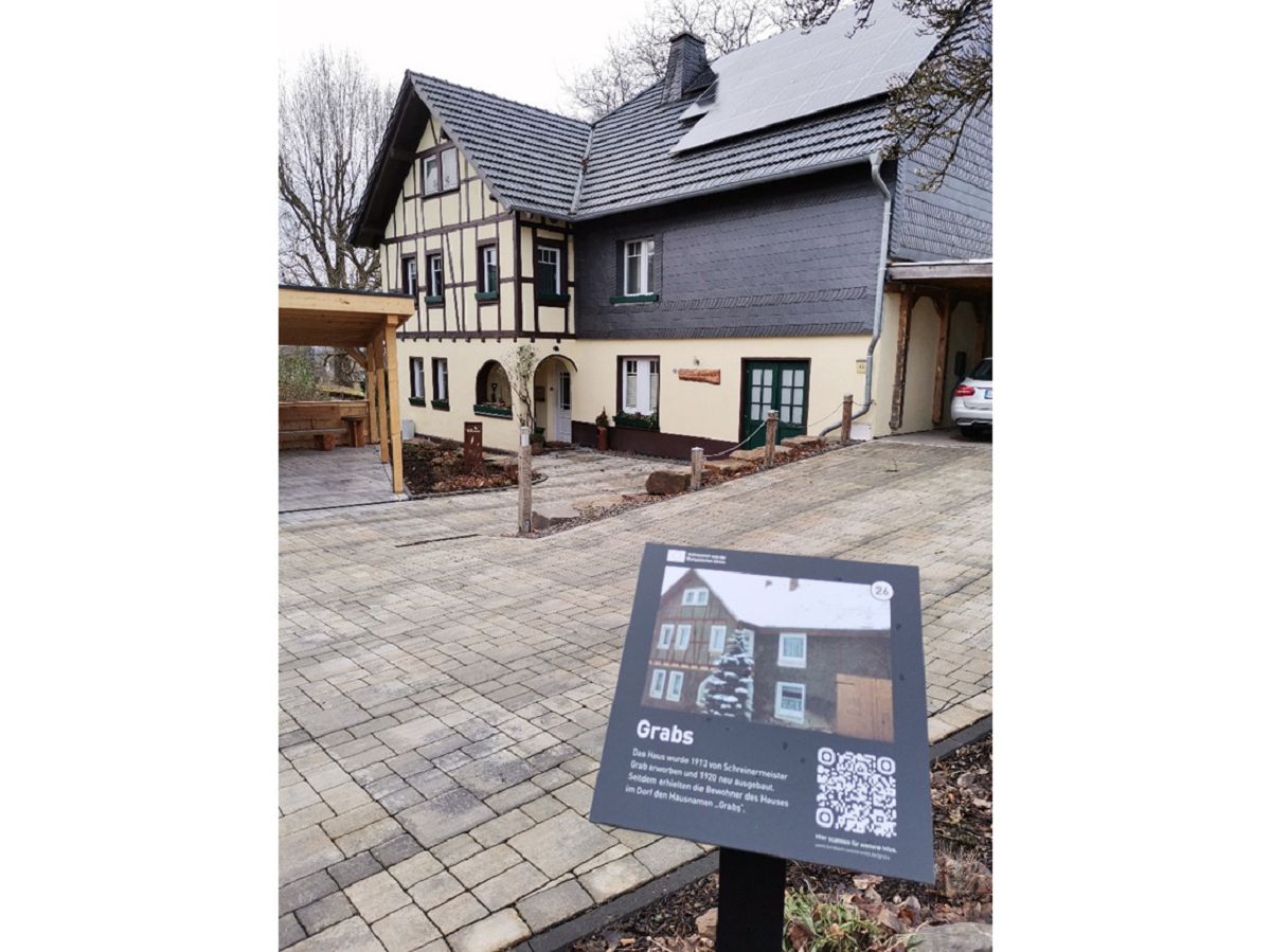 Das Haus Grabs in Birnbach, ein prgnantes Beispiel des Projekts Birnbacher Hausschilder. Die Tafel zeigt den Hausnamen, historische Details und einen QR-Code, der zu weiterfhrenden Informationen fhrt. (Bildquelle: VG Altenkirchen-Flammersfeld)