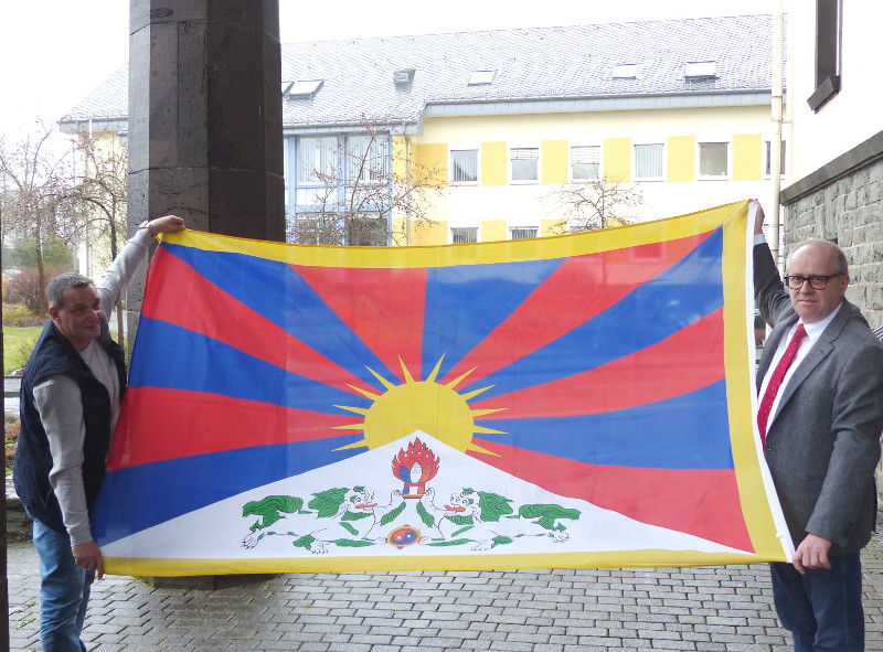 Landrat Dr. Peter Enders (rechts) und Hausmeister Rainer Scherm mit der Tibet-Flagge, die zum Jahrestag des tibetischen Volksaufstandes von 1959 wieder am Kreishaus in Altenkirchen gehisst wurde. Foto: Kreisverwaltung  
