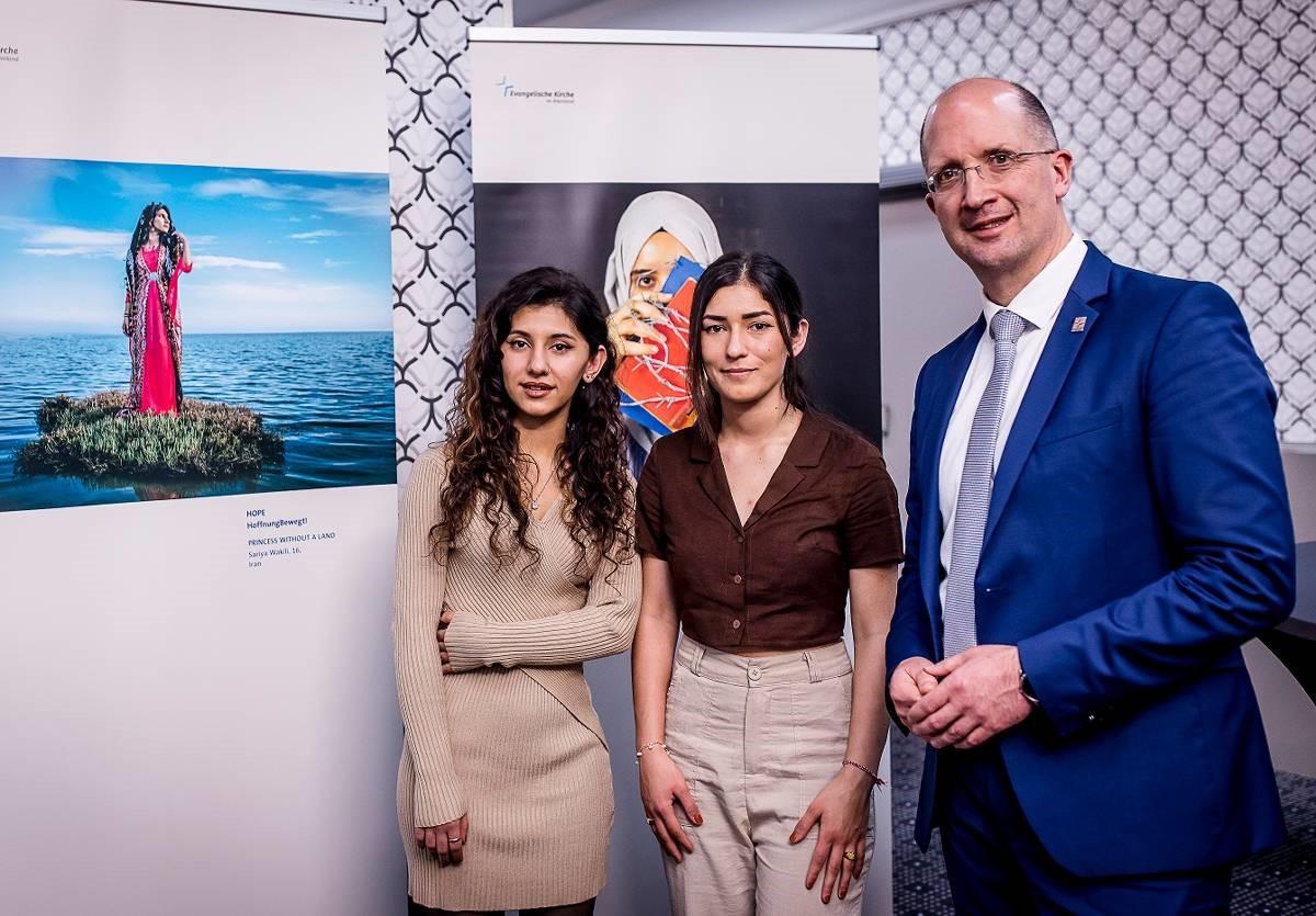 Saria Wakili und Asifa Hassan, Teilnehmerinnen des Fotoprojekts, mit Dr. Thorsten Latzel, Prses der Evangelischen Kirche im Rheinland, vor Bildern der Ausstellung. (Foto: Saria Wakili/ Asifa Hassan )
