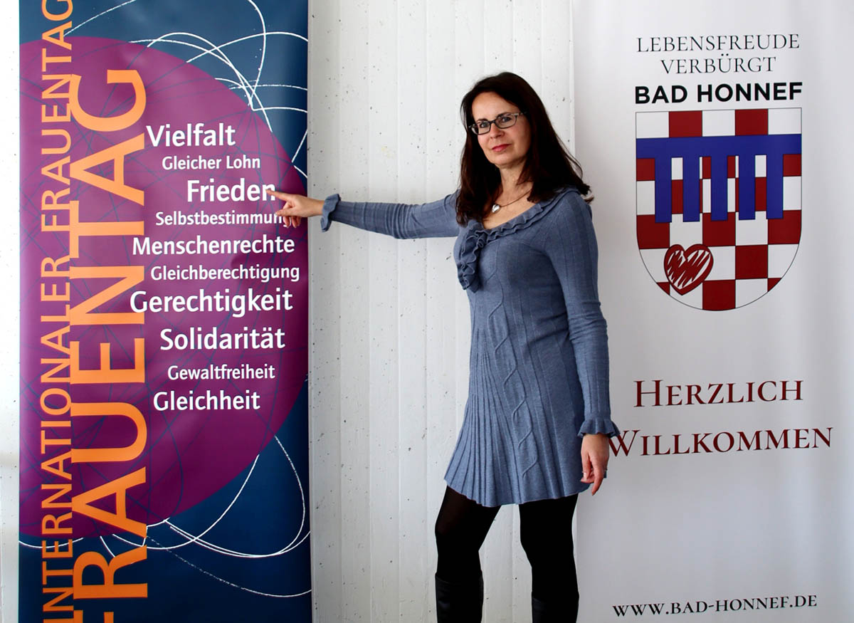 Gleichstellungsbeauftragte der Stadt Bad Honnef Iris Schwarz vor dem Rollplakat zum Weltfrauentag des Vereins Gleichberechtigung und Vernetzung. Foto: Stadt Bad Honnef