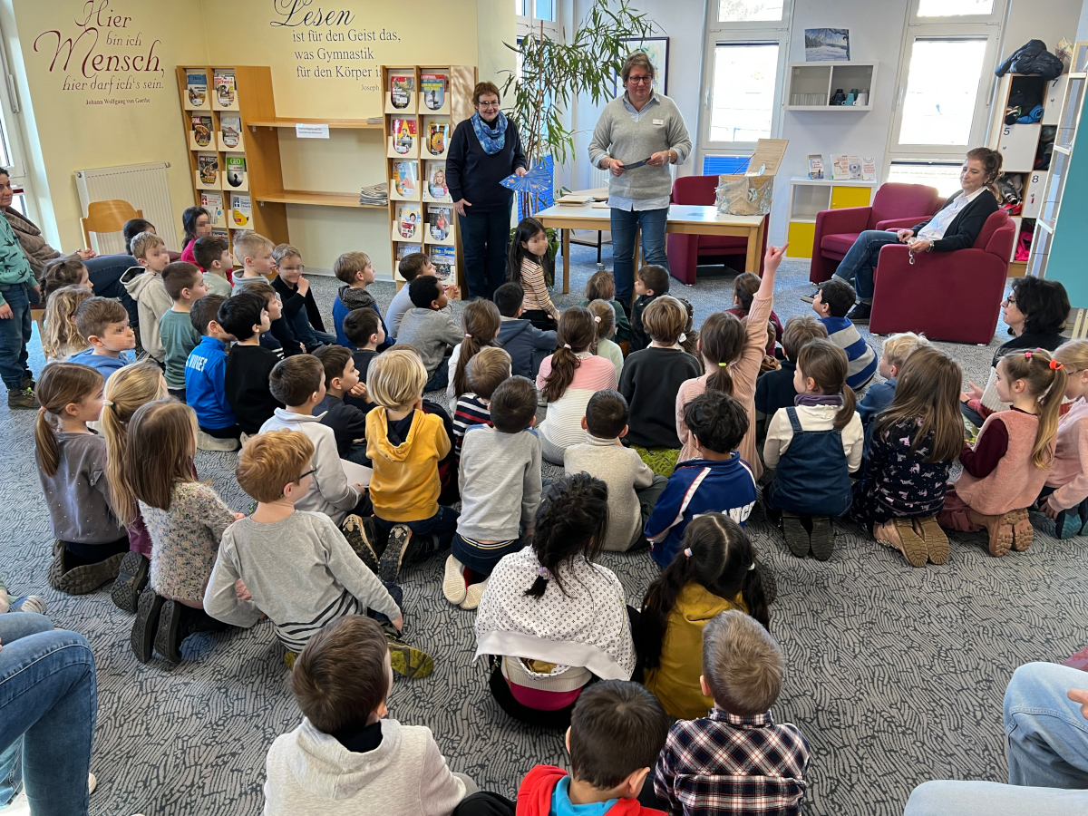 Aufmerksam verfolgen die Grundschler der Joseph-Kehrrein-Schule in der Montabaurer Stadtbibliothek die Verlosung, die Klaudia Zude und Susanne Walter-Hahn durchfhrten. Anschlieend lauschten die Kinder der Lesung von Ursula Kingen (von links). 
(Foto: Stadt Montabaur/Holger Pritzsch)