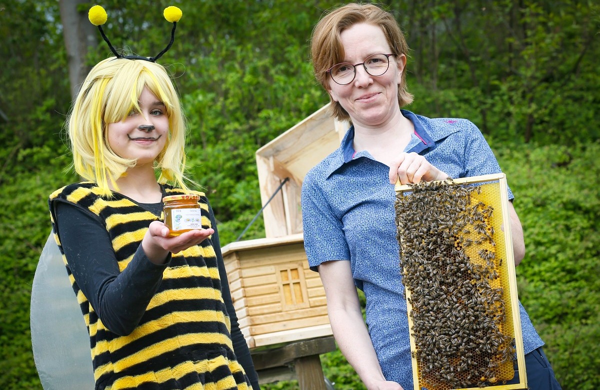 Ida (12) mit fr die Premiere produzierten Honig und Imkerin Sandra Denker mit einer Bienenwabe aus dem dahinter zu sehenden Schaukasten. (Foto: Anke Hesse)