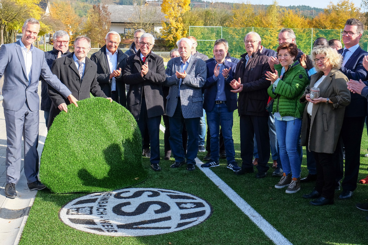 SSV-Prsident Martin Reuschenbach, Erster Kreisbeigeordneter Michael Mahler, Oberbrgermeister Jan Einig, Landrat Achim Hallerbach, Minister Roger Lewentz und FV Rheinland-Prsident Walter Desch (vorne, von links) enthllen feierlich das in den Kunstrasen eingearbeitete Logo des SSV Heimbach-Weis. (Foto: Pressebro Stadt Neuwied)
