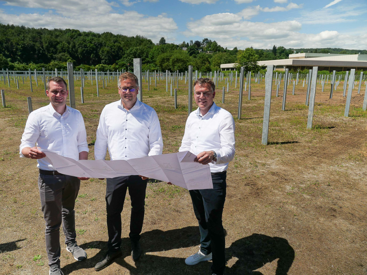 Auf dem zwei Hektar groen Areal neben der Raiffeisendruckerei entsteht der neue Solarpark. Bereichsleiter Udo Stmper sowie Thomas Kill und Julian Scherhag von der SWN Green Energy verfolgen den Aufbau. Aktuell werden die Unterkonstruktionen fr die Module installiert. (Foto: SWN Green Energy)