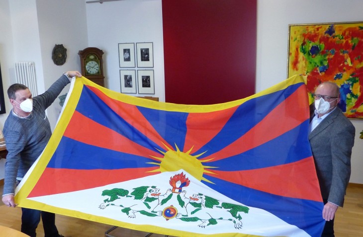 Archivbild von 2021: Landrat Dr. Peter Enders (rechts) und Hausmeister Rainer Scherm von der Kreisverwaltung mit der Tibet-Flagge, die zum Jahrestag des tibetischen Volksaufstandes von 1959 auch in diesem Jahr wieder am Kreishaus in Altenkirchen gehisst wird. (Foto: Kreisverwaltung)