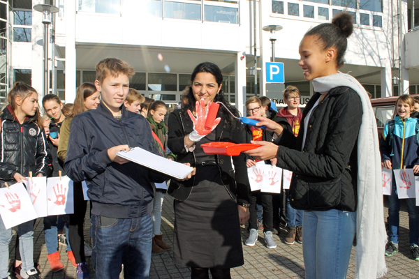 Konfirmandin Anna Schwager nimmt einen roten Abdruck der Hand von Erster Beigeordneter Cigdem Bern (Mitte) fr die Aktion-Rote-Hand, um gegen den Einsatz von Kindersoldaten zu protestieren. Foto: Privat