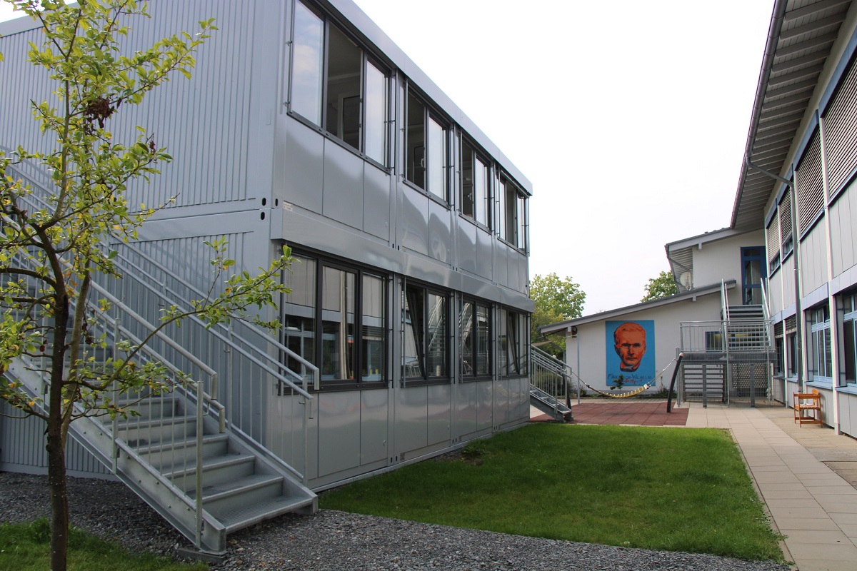 Links die beiden Container, rechts das massive Schulhaus. (Foto: Patt)