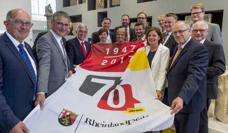 Ministerprsidentin Malu Dreyer, Landtagsprsident Hendrik Hering und Innenminister Roger Lewentz bergaben die Jubilumsfahne an die Abgeordneten. Foto: Landtag Rheinland-Pfalz/Silz.