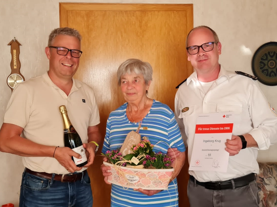 Volker Hammer (links) und Holger Mies bergaben die Urkunde und ein Geschenk an Ingeborg Krug. (Foto: DRK)