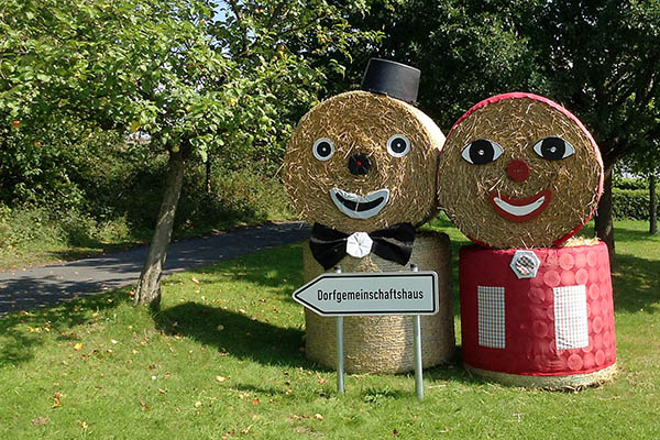 Resi und Toni, die beiden Strohfiguren, weisen den Besuchern den Weg zum Dorfgemeinschaftshaus, wo in diesem Jahr wieder samstags und montags gefeiert wird. Foto: Gemeinde