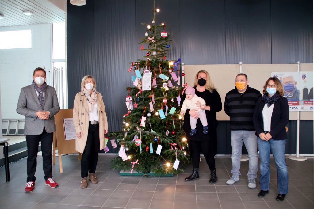 Der Weihnachtswunschbaum im Foyer des Rathauses  bei der Erffnung v. l.: Erster Beigeordneter Holger Heuser, Katja Hurrelmann (Bndnis fr Familie), Laura Solzbacher (Bndnis fr Familie) mit Lena, Frank Lw (Fachdienst Soziales und Asyl) und Nadine Batzella (Leiterin Fachdienst Soziales und Asyl). Foto: privat